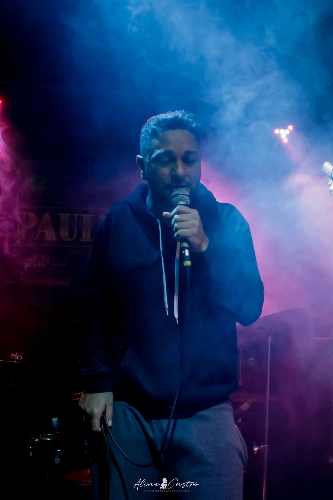 Cantando no palco em meio à fumaça azul e rosa