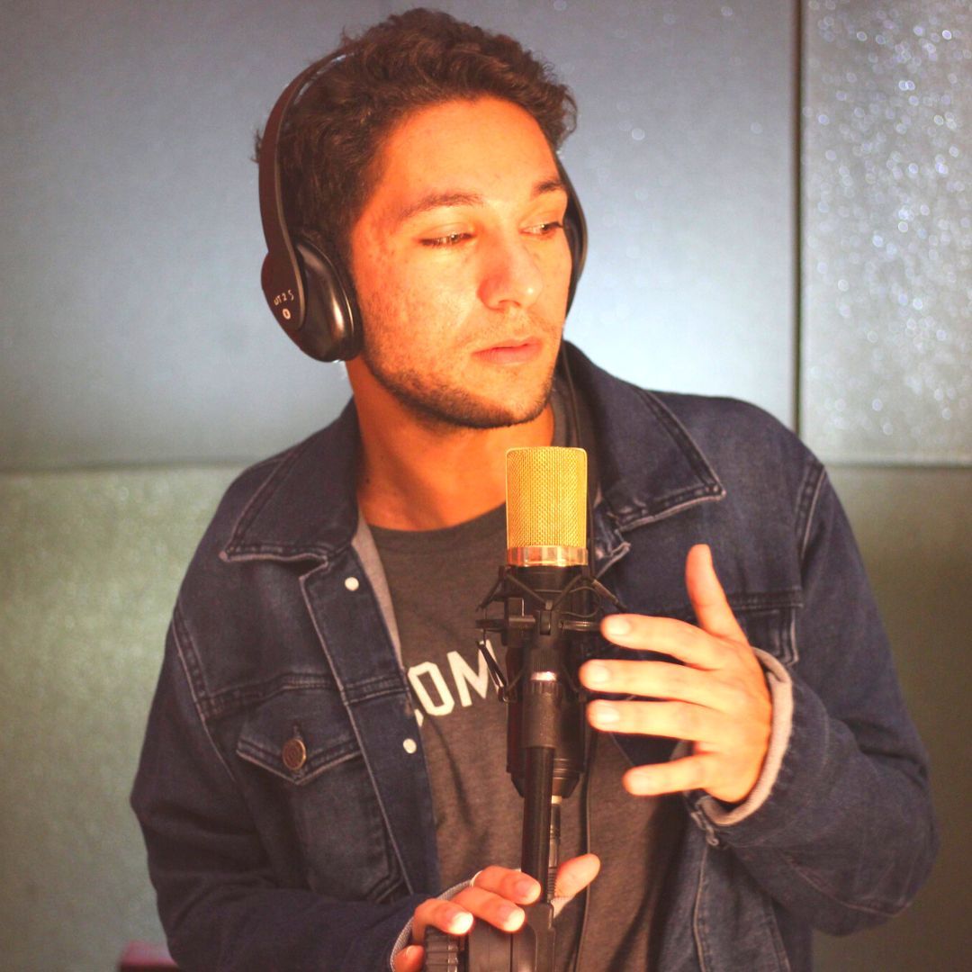 No estúdio, de fones de ouvido, diante de um microfone dourado